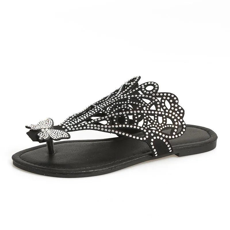 Women's black slip-on sandals with rhinestone flip-toe design and hollow detailing on the upper.