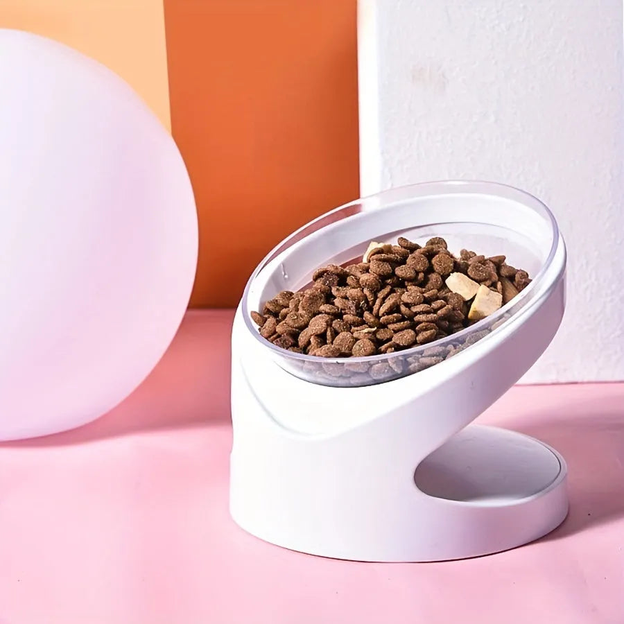 Clear plastic tilted cat food bowl on a flat surface