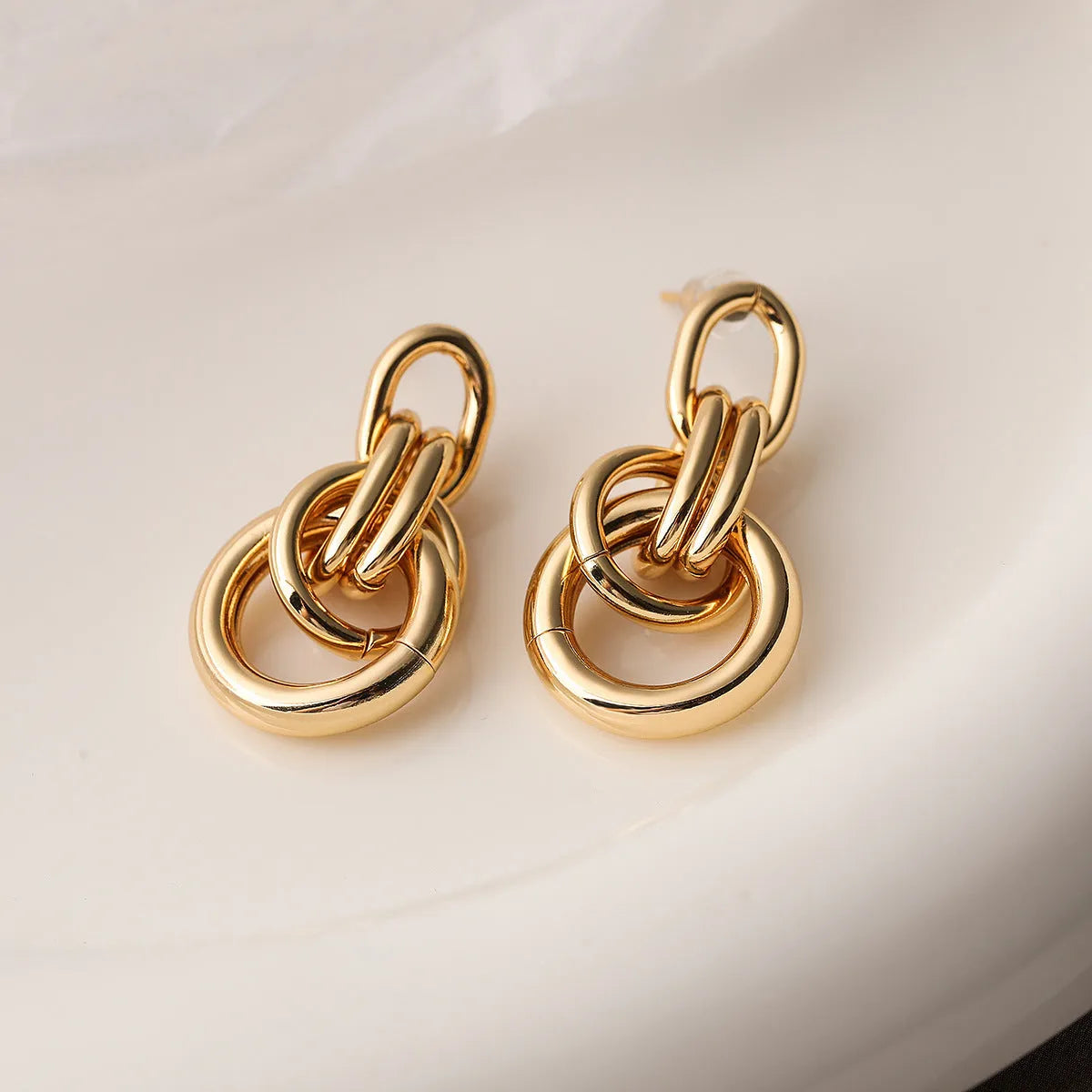 A pair of gold-toned geometric drop earrings with an irregular shape, made from copper.