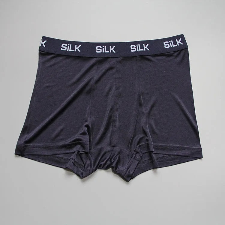 Man wearing loose-fit silk shorts in navy blue, showing casual style and breathable design.