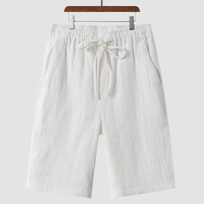 Man wearing beige linen cropped shorts with a loose fit and elasticated waist