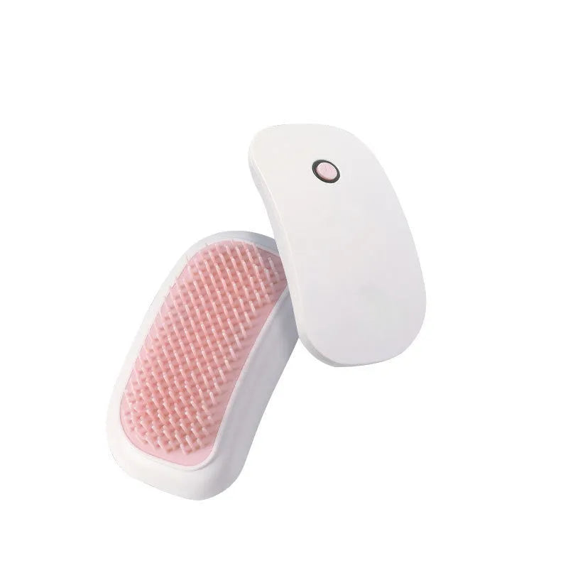 Handheld pink and white electric pet massage brush for cats and dogs on a table.