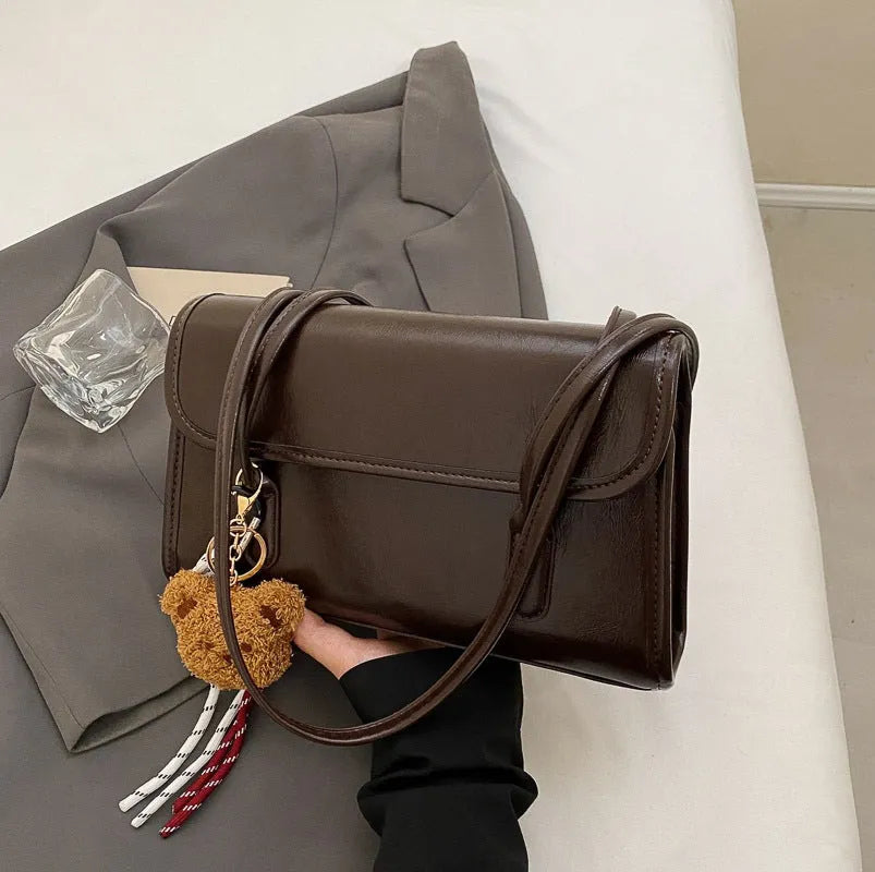Women's brown PU leather square shoulder bag with pendant accessory showing interior zipper compartment
