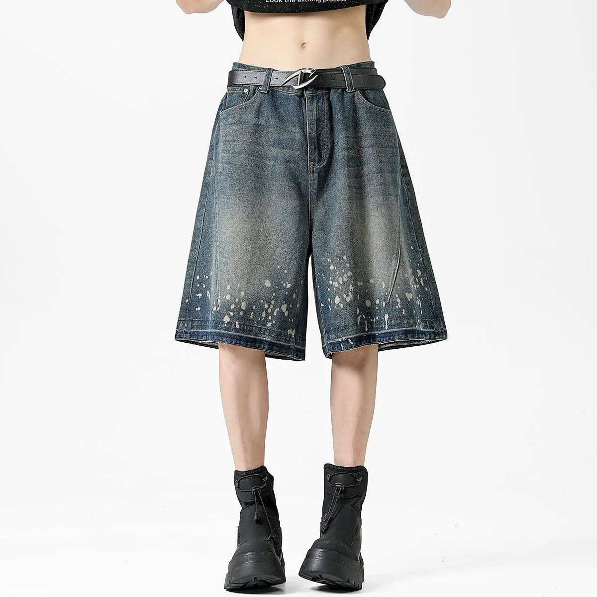 Man wearing retro blue denim shorts with ripped and splash-ink distressing on a straight-leg cut.