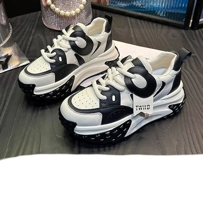 A pair of thick-soled leather casual shoes in a black and white colourway, showing the round toe and lace-up front.