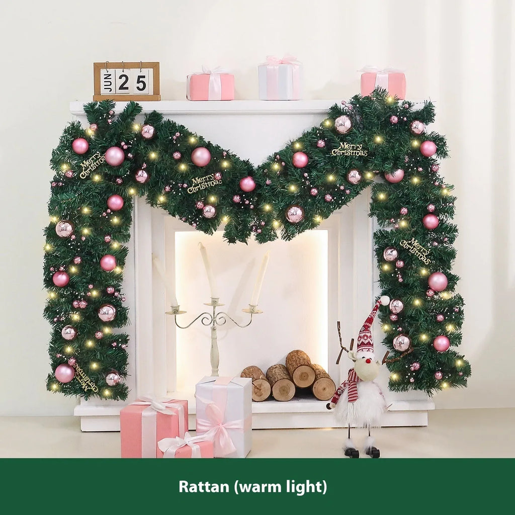 Pink artificial rattan Christmas garland with small fruit details and warm white LED lights, coiled to show its 2.7m length.