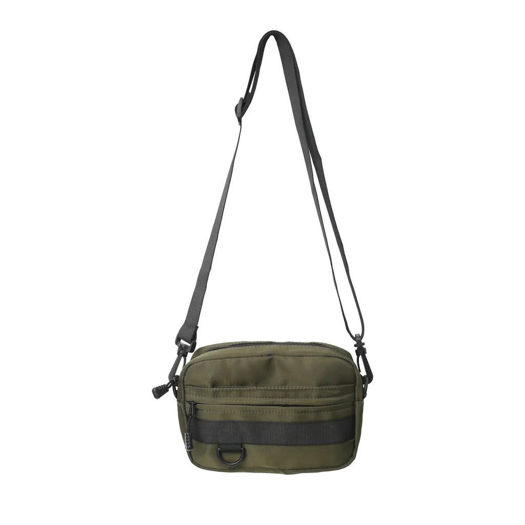 Men's solid colour nylon messenger bag with crossbody strap, shown in street style.