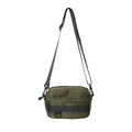 Men's solid colour nylon messenger bag with crossbody strap, shown in street style.