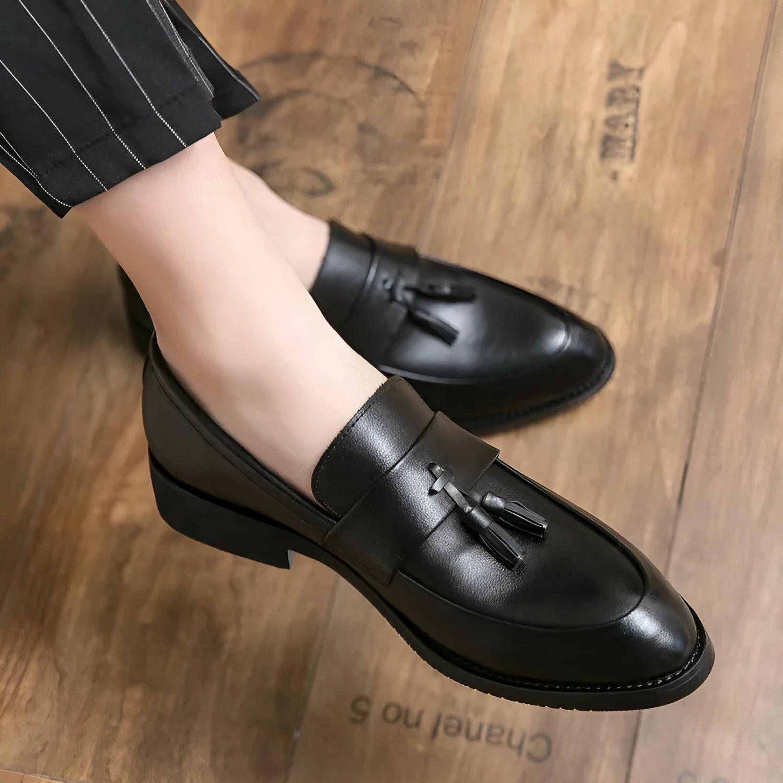 Men's black slip-on business casual shoes with a tassel detail on the artificial PU upper