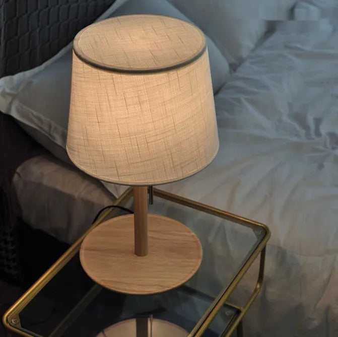 Walnut coloured solid wood desk lamp with a white fabric lampshade and a cable switch.