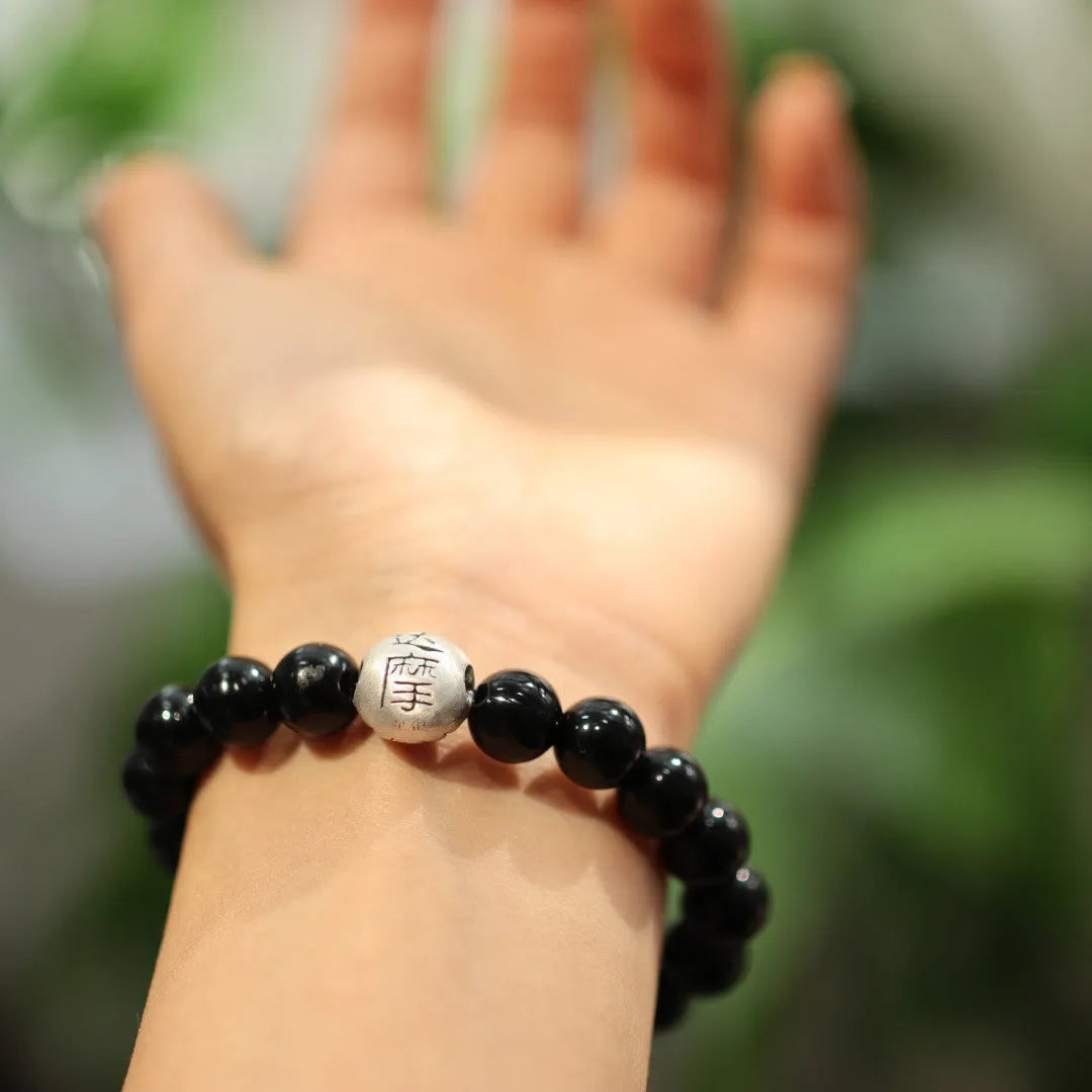 Close-up of a women's bracelet with large black agate beads and sterling silver, showing Chinese style design.