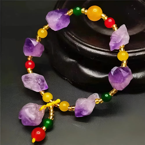 Women's amethyst bracelet with natural shaped beads and a fu character charm on an adjustable band.
