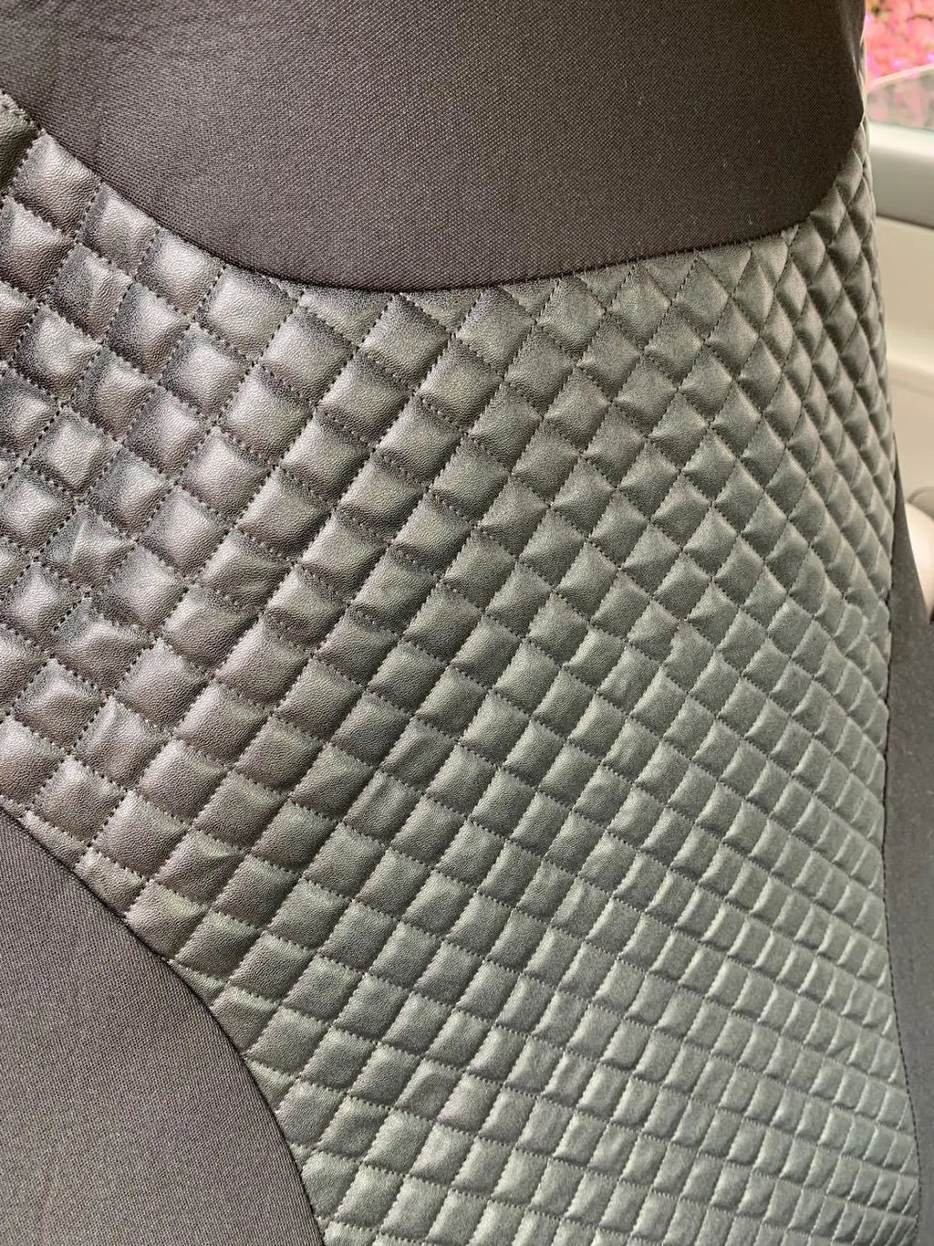 Black quilted automotive seat cover with PU and polyester construction shown on car seat
