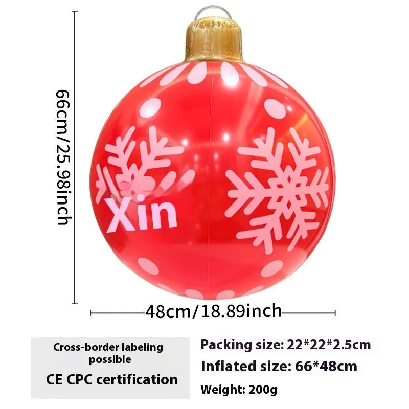 Large red and white inflatable Christmas ball with snowflake design in garden setting