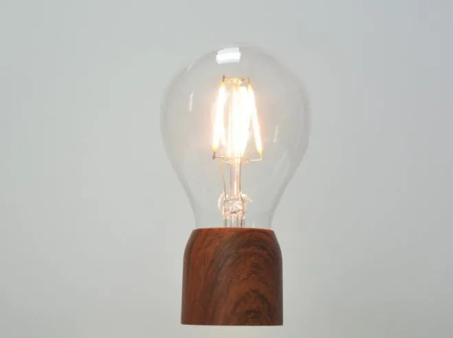 Magnetic levitation floating light bulb hovering above imitation wood base with universal voltage specification