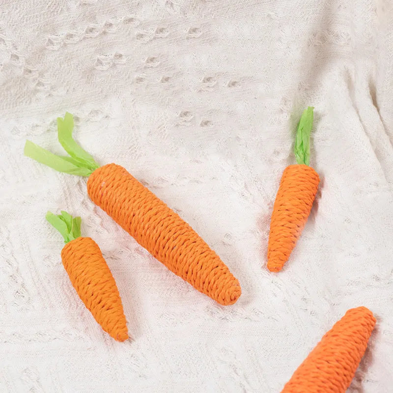 Assortment of cat toys including paper carrots, plastic ringing stones, and wooden grinding sticks on a plain background.