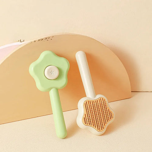 Green stainless steel self-cleaning cat comb with needle bristles on a white background.