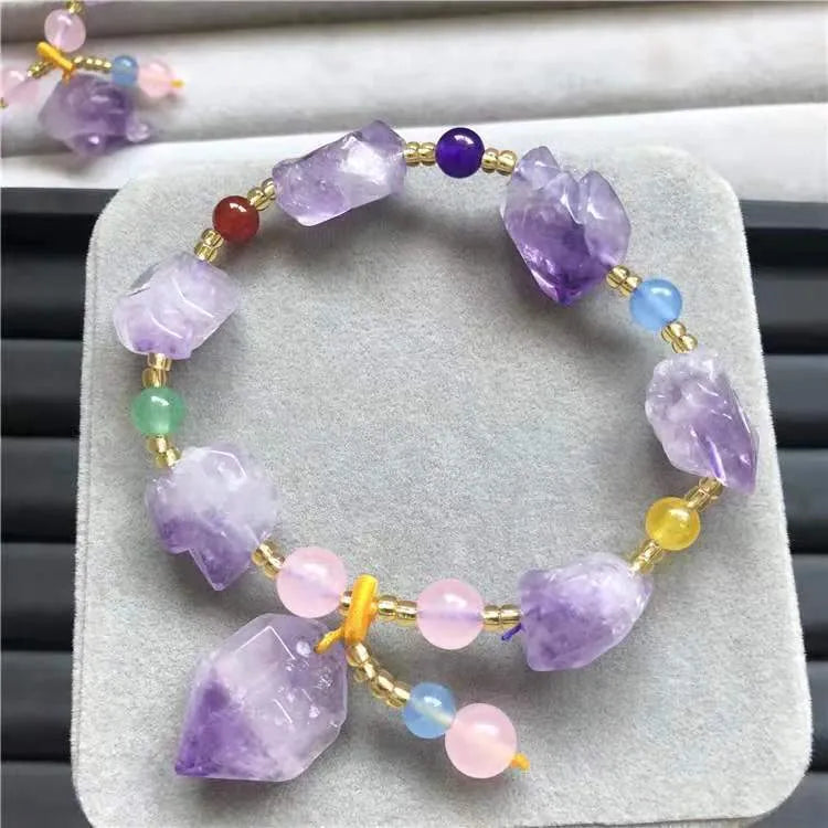 Women's amethyst bracelet with natural shaped beads and a fu character charm on an adjustable band.