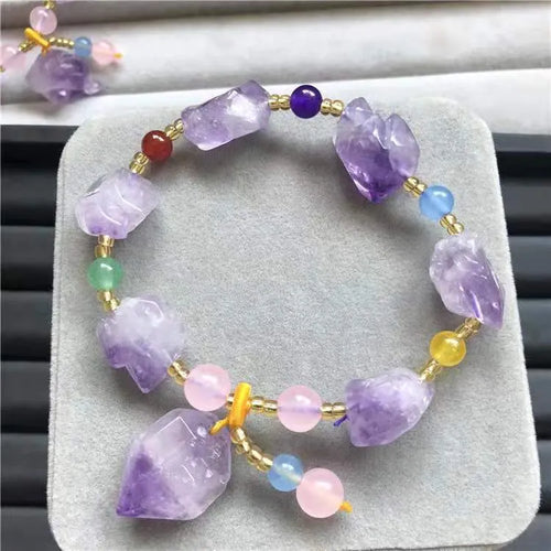 Women's amethyst bracelet with natural shaped beads and a fu character charm on an adjustable band.