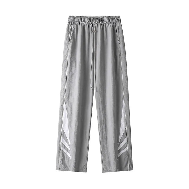 Men's black straight leg loose fit summer sports trousers with an elastic waist on a grey background.
