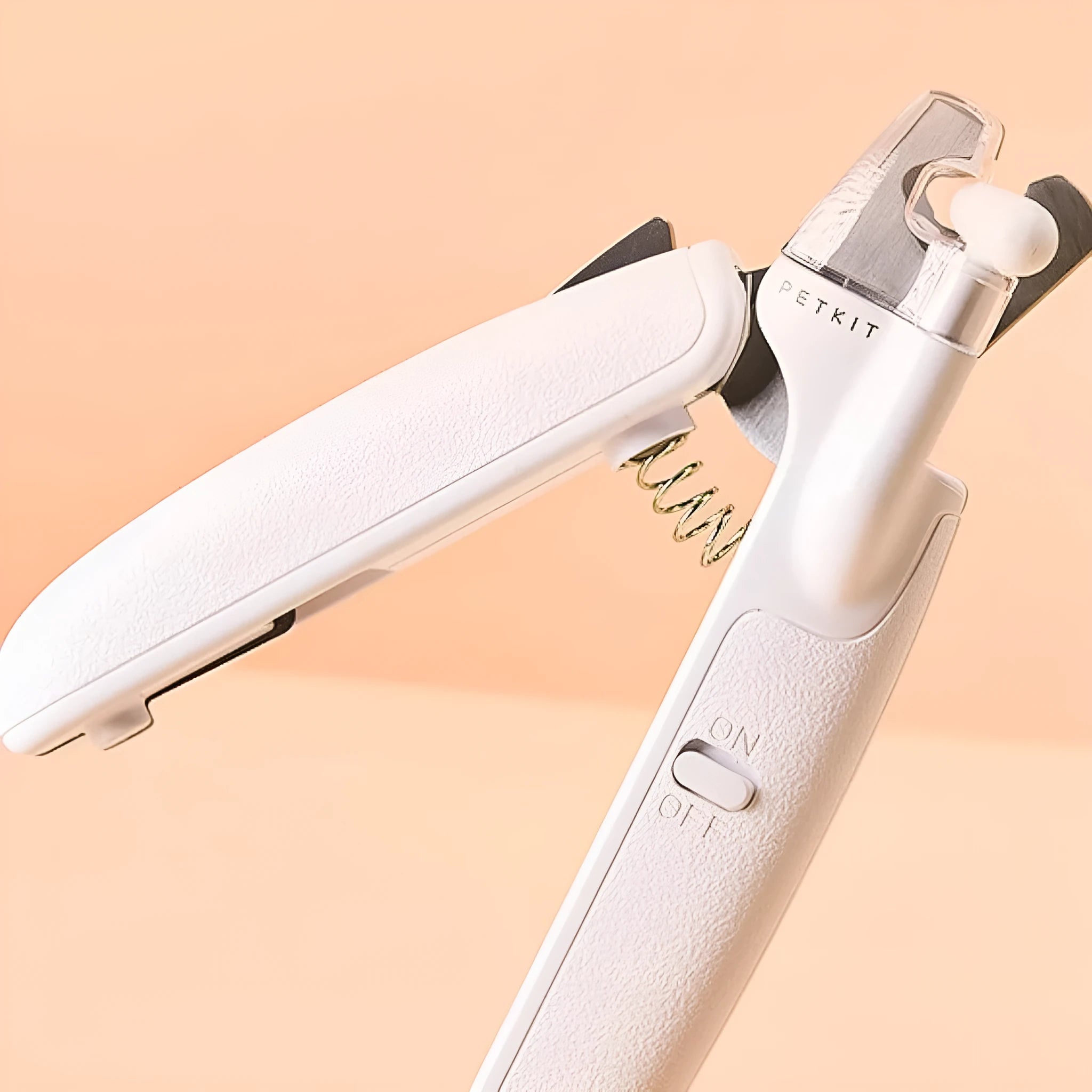 White pet nail clippers with LED light, open transparent splash guard, and separate nail file on a table