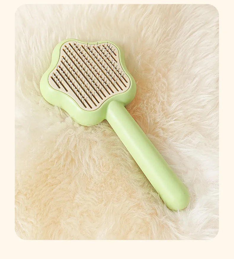 Green stainless steel self-cleaning cat comb with needle bristles on a white background.