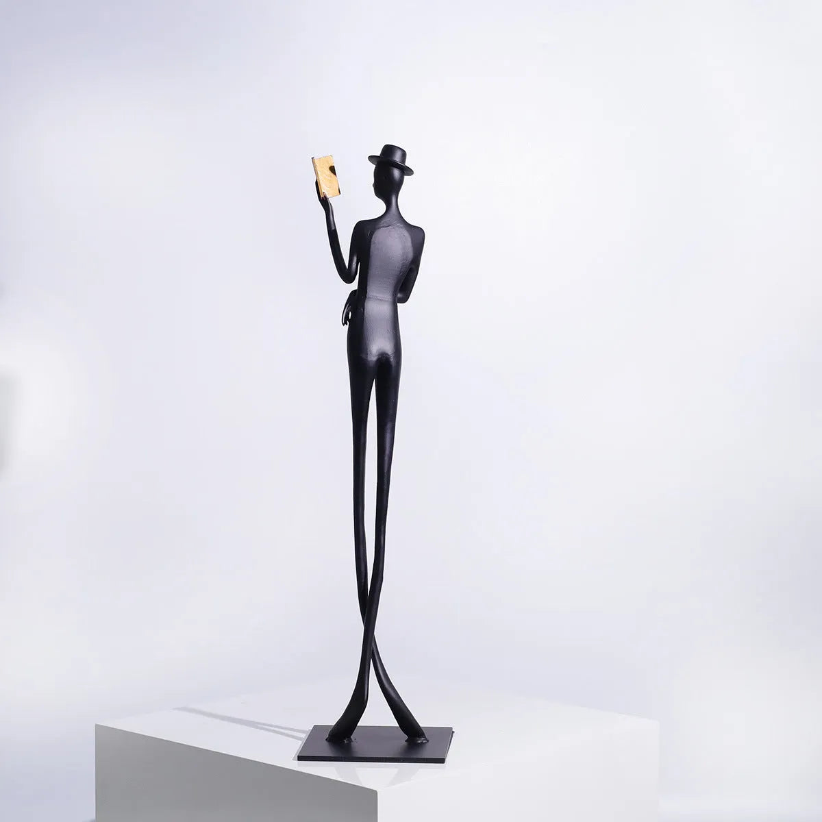Black metal cast aluminium sculpture of reading woman on square base