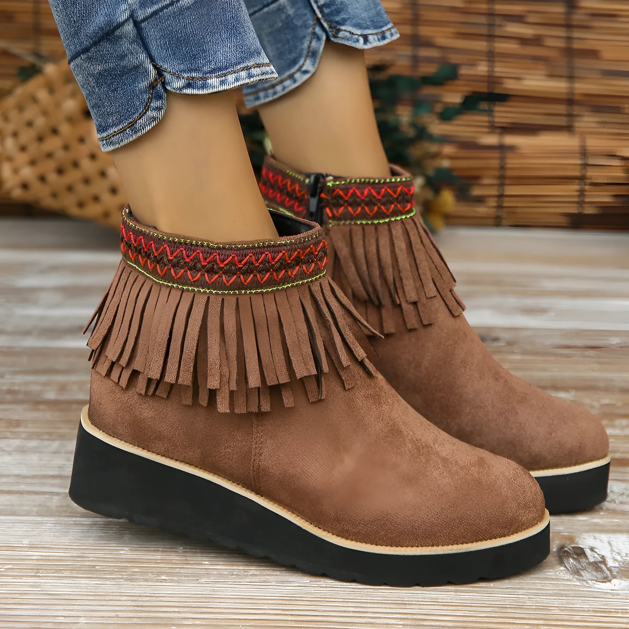 Women's dark brown suede ankle boots with a wedge heel, side zip, and decorative tassel detail.