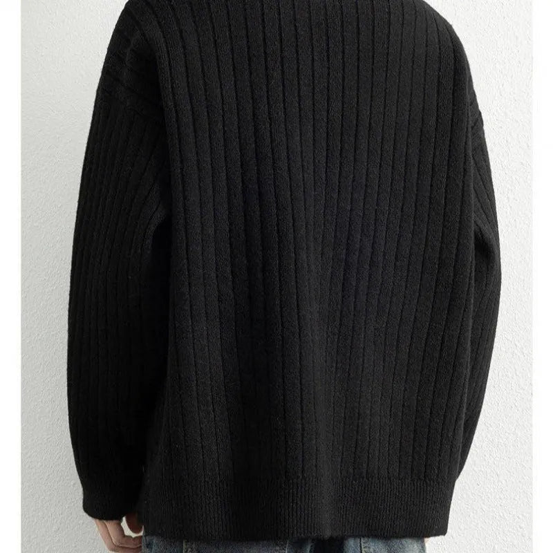 Man wearing a grey half-zip loose knit sweater, showing the textured fabric and front zip.