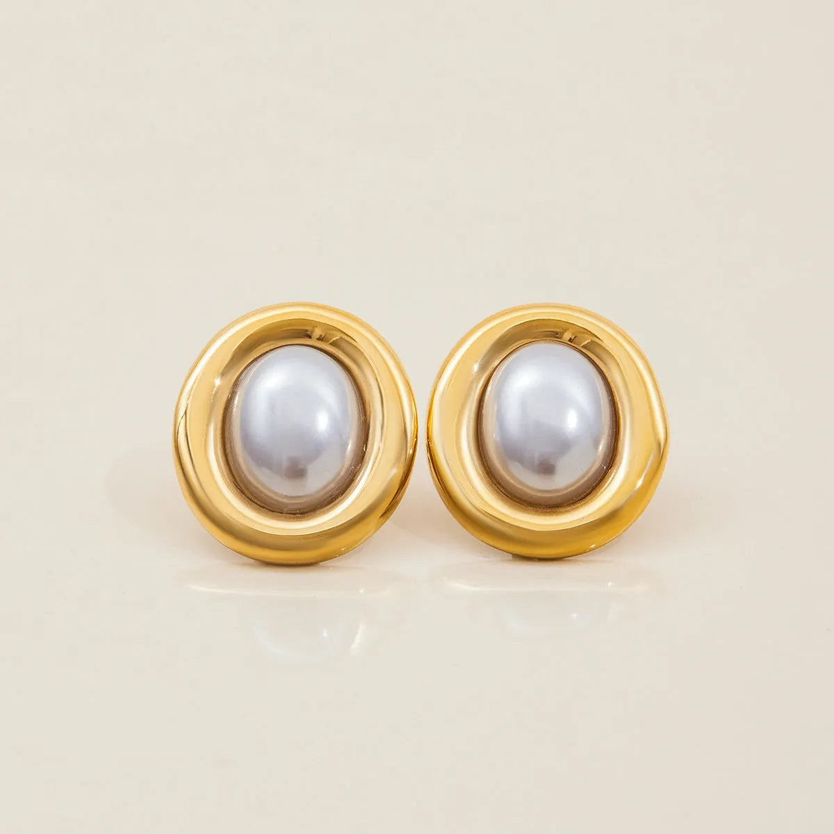 A pair of stainless steel stud earrings for women featuring a single vintage pearl, with butterfly clutch backings visible.