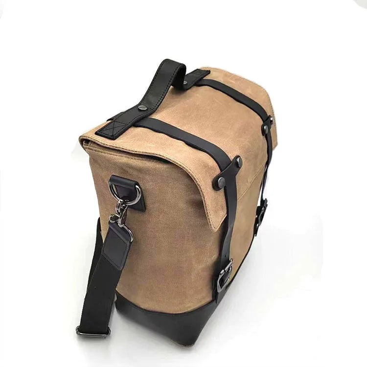 Black waterproof canvas motorcycle side pannier bag with cowhide accents showing mounting straps