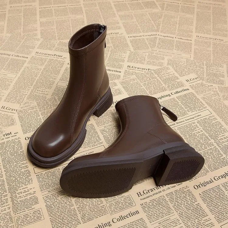Women's black ankle boots with a flat heel, round toe, and a back zip fastening on a rubber sole.