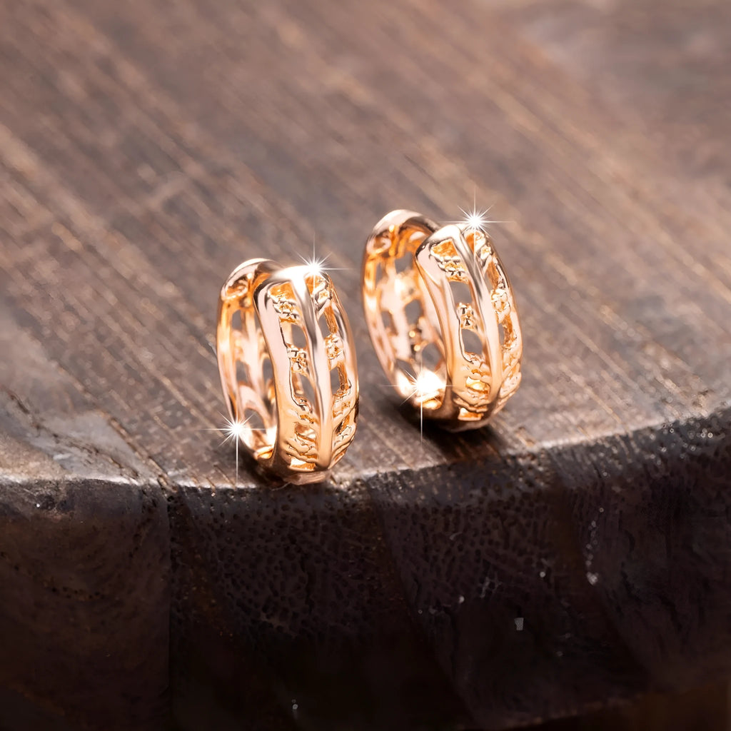 Small copper earrings with a hollowed-out heart-shaped leaf design in rose gold finish.