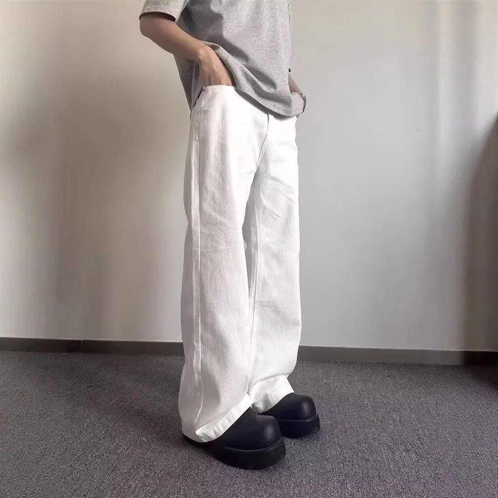 A pair of men's white wide-leg straight jeans with a mid-rise waist and zipper fly on a plain background.