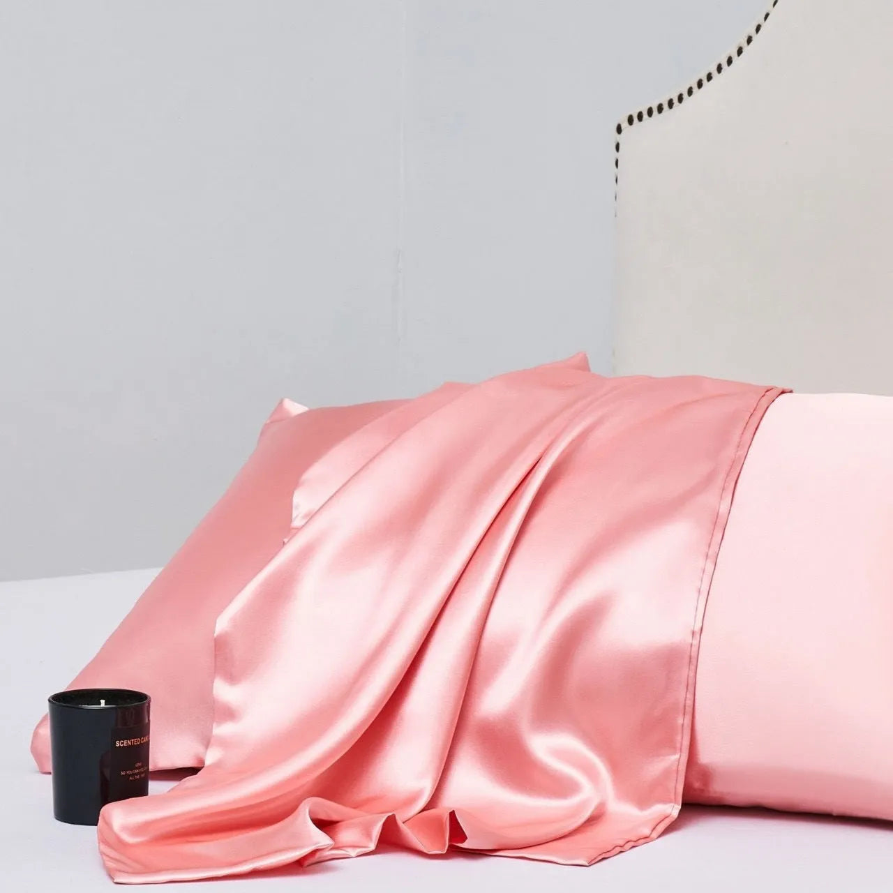 Pair of solid colour satin pillowcases in polyester fabric on a bed.