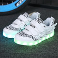 Children's plum red sneakers with multicolour LED lights glowing on the soles.