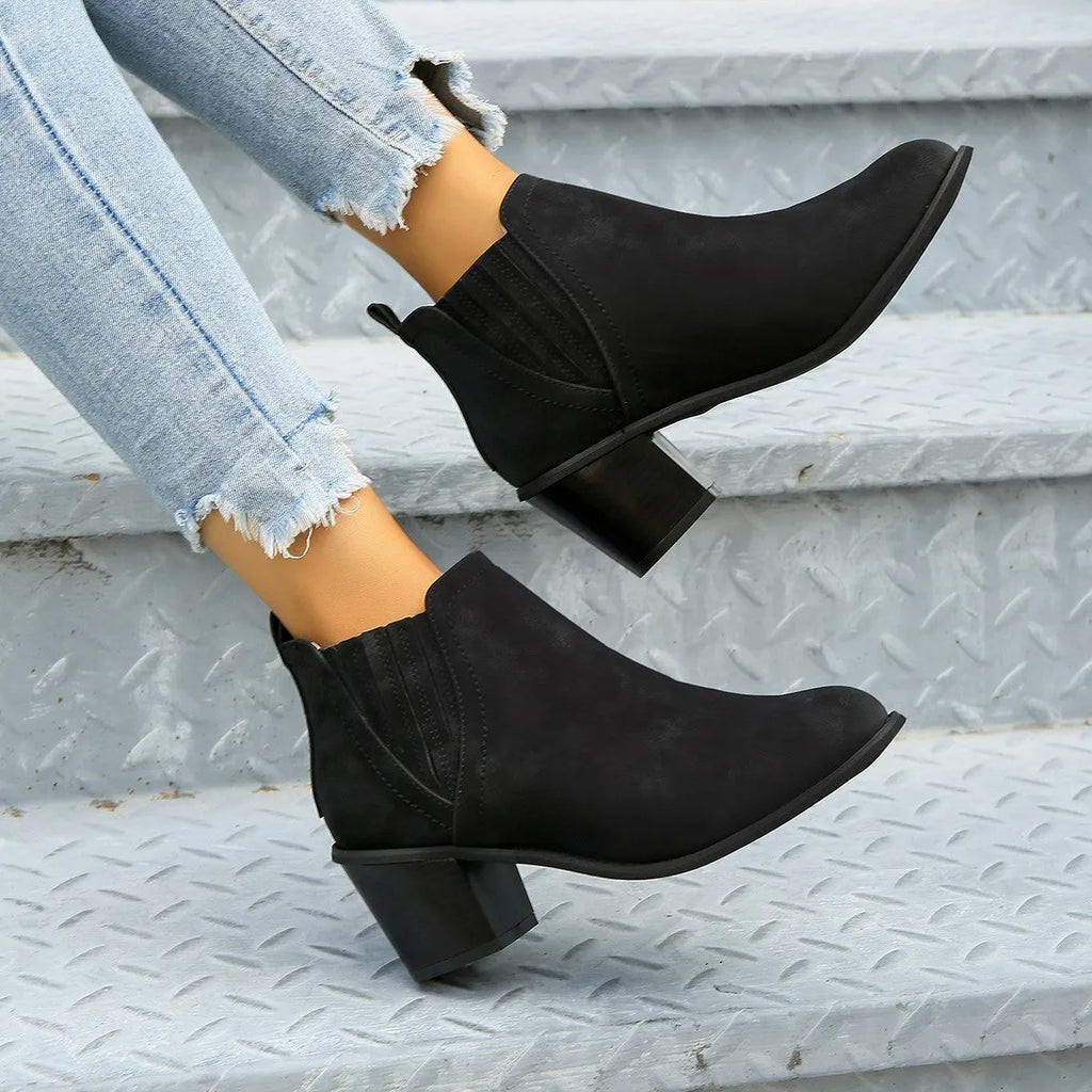 Black women's ankle boots with a pointed toe, thick square low heel, and slip-on design on a white background.