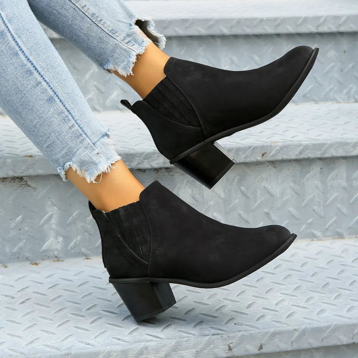 Black women's ankle boots with a pointed toe, thick square low heel, and slip-on design on a white background.