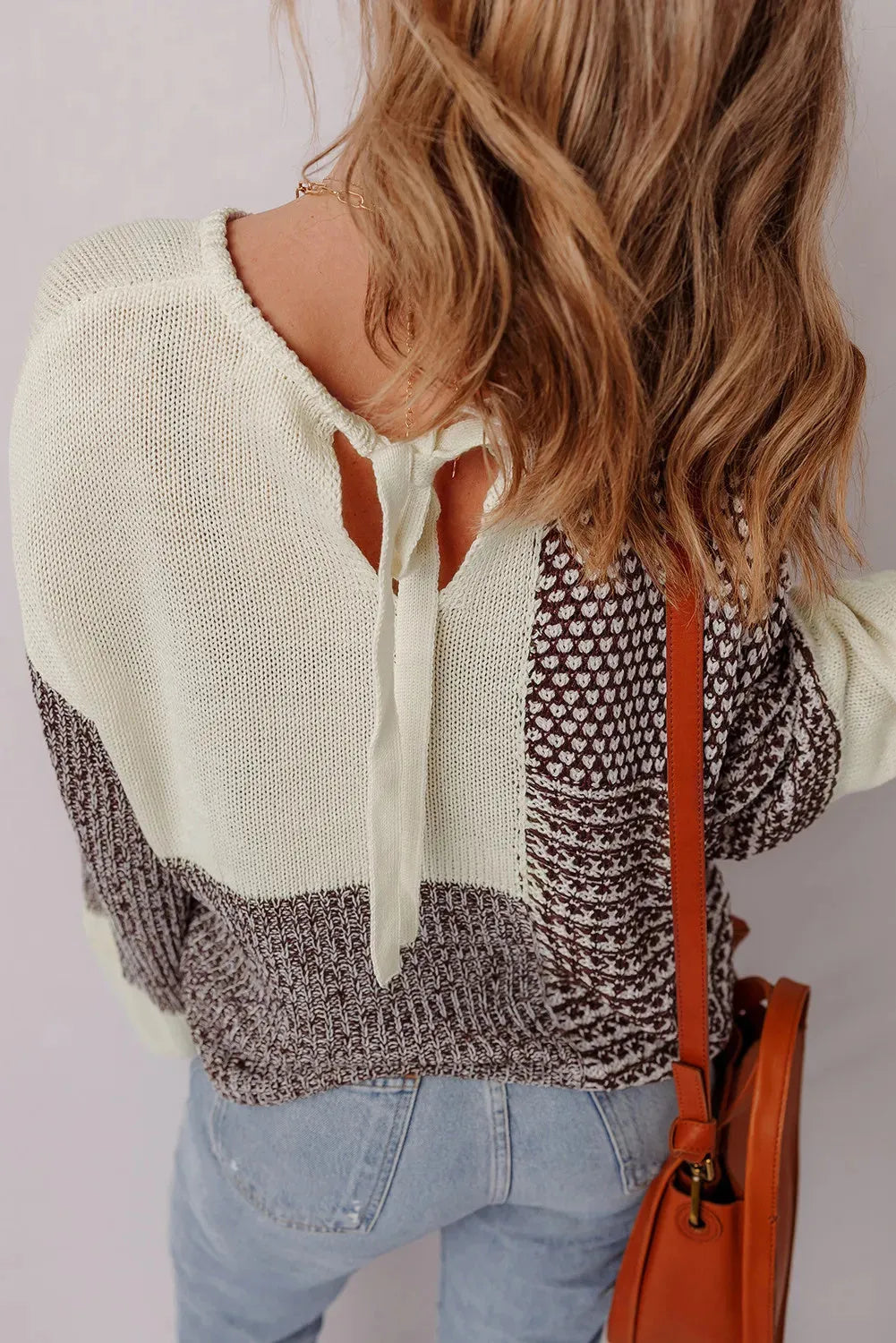 Dark khaki colour block loose sweater with back tie and drop shoulders on a hanger.