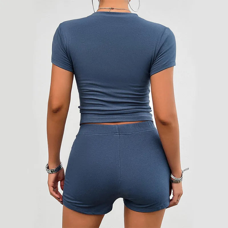 Women's solid colour two-piece sports set with round neck t-shirt and elastic shorts.