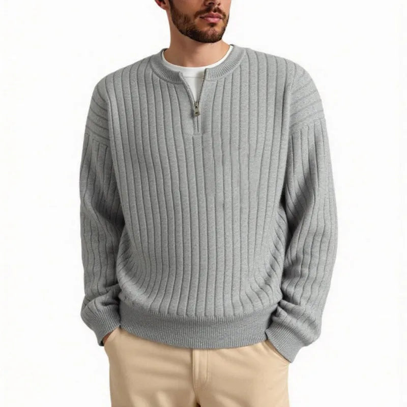 Man wearing a grey half-zip loose knit sweater, showing the textured fabric and front zip.