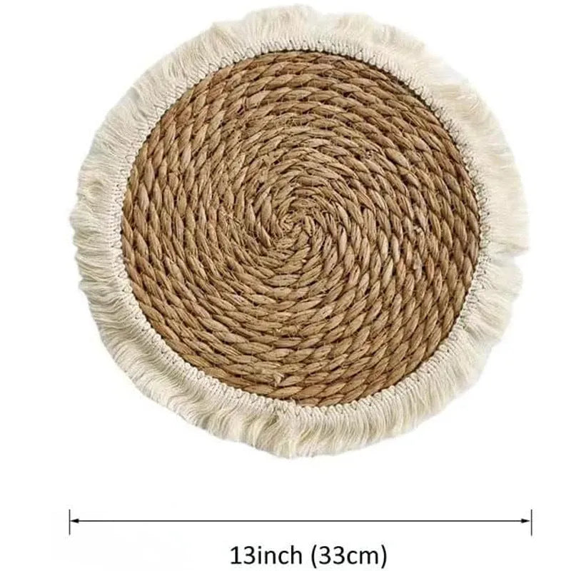 Round natural papyrus placemat with corn rope tassel trim on a wooden table.