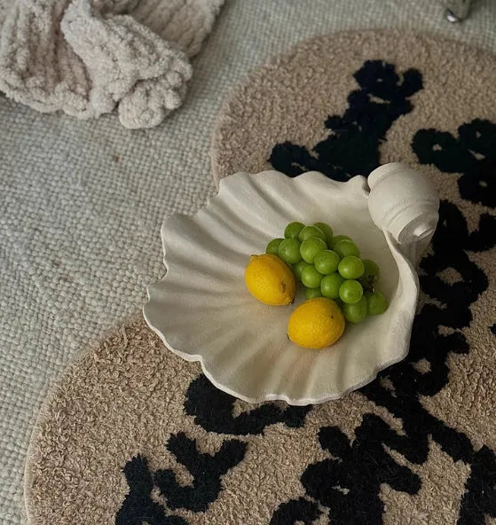 Close-up of a white resin decorative ornament with a detailed seashell design for fruit plates and table displays.
