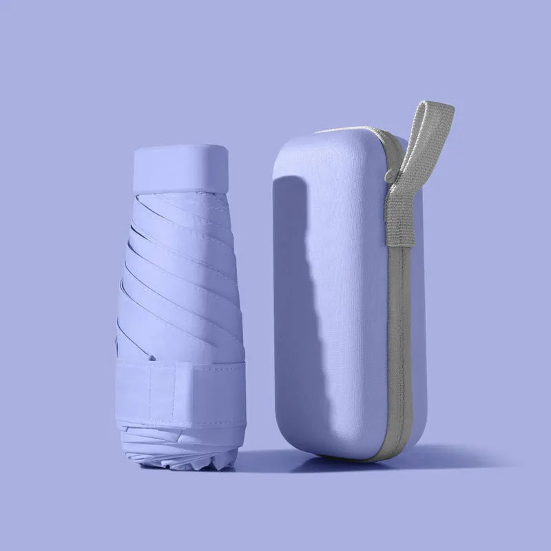 A folded six-fold flat umbrella in a capsule box, showing the steel ribs and rubber handle.
