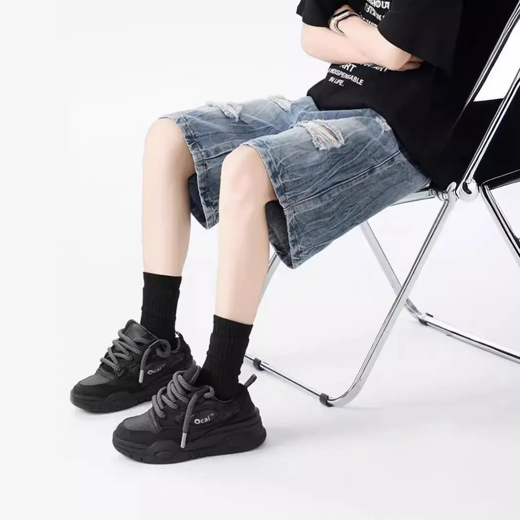 Man's loose-fit ripped denim shorts in washed black showing distressed details and retro styling