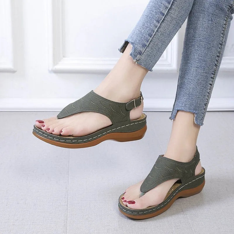 Women's black casual wedge heel flip flop sandals showing adjustable back buckle strap and solid colour design.
