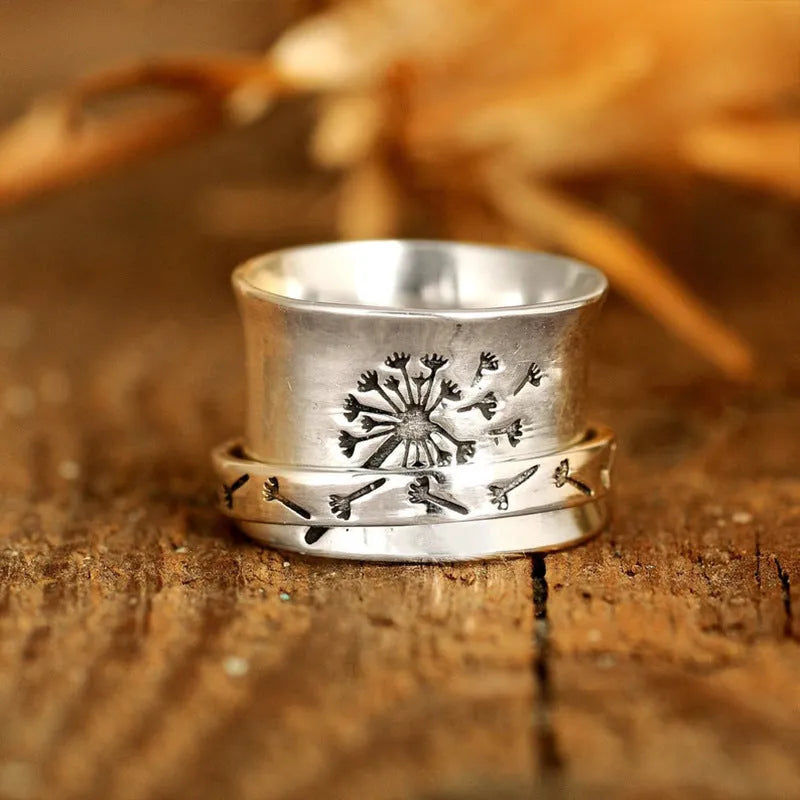 Silver rotatable flower ring on a finger showing the floral design.