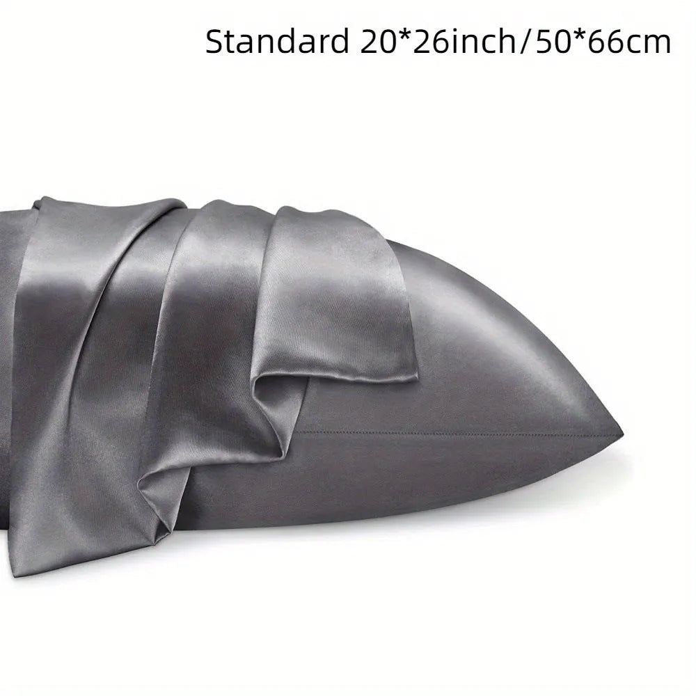 Pair of solid colour satin pillowcases in polyester fabric on a bed.