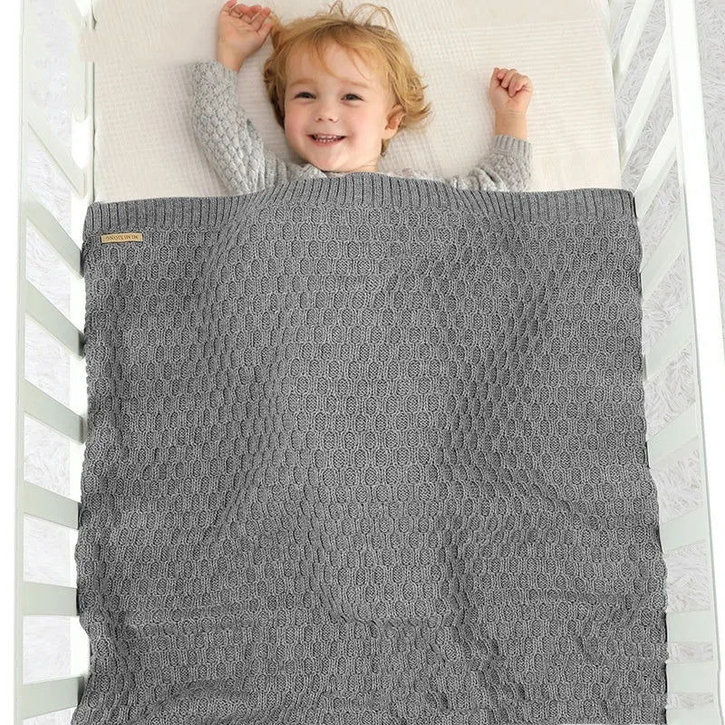 Solid colour infant hug blanket with three-dimensional line texture, shown in a choice of colours.