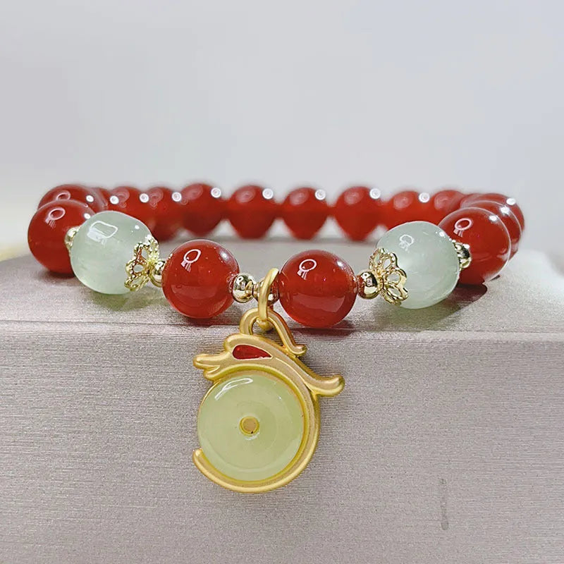 A red agate bracelet for women with Chinese style dragon and lucky bag motifs.
